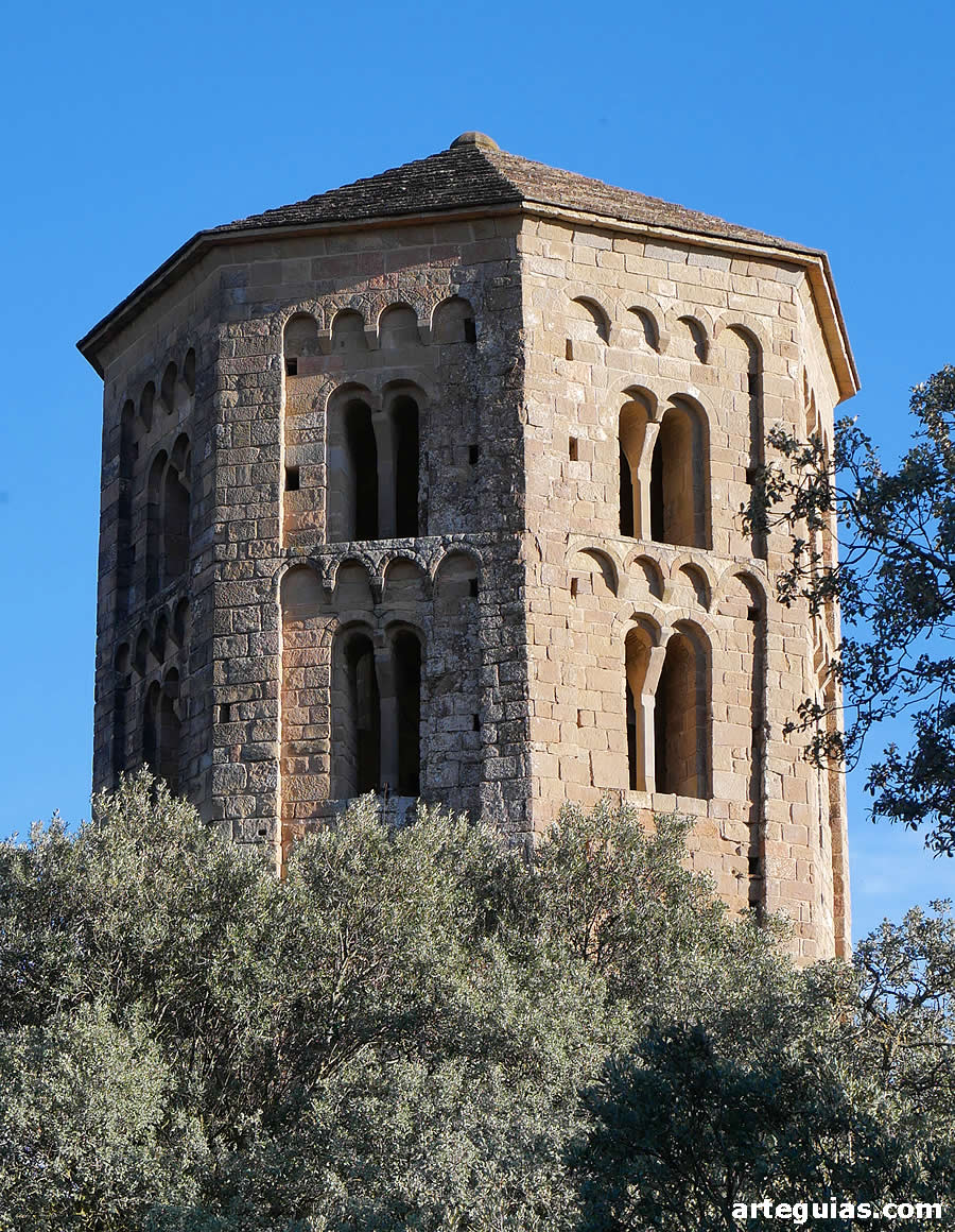Los huecos de campanas de la torre campanario despuntan sobre encinas y olivos